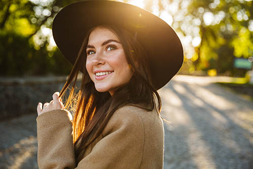 woman smiling outdoors wearing hat