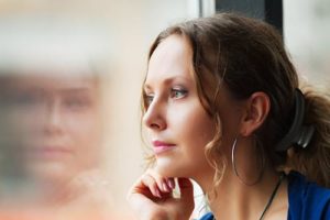 woman looking out window wondering what is addiction