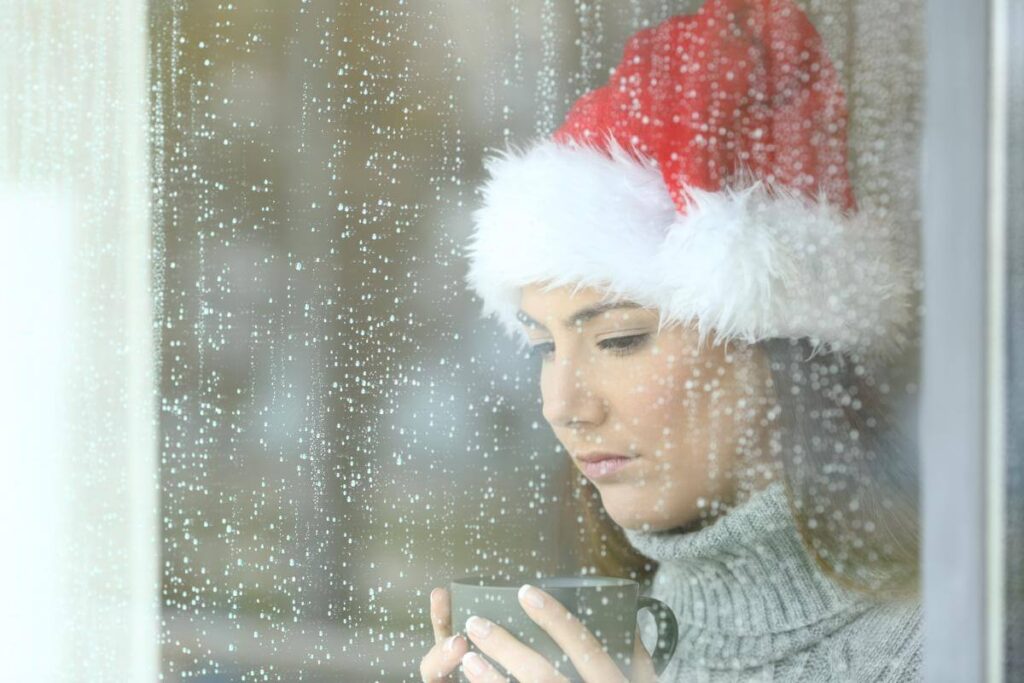 person with holiday anxiety looking out window