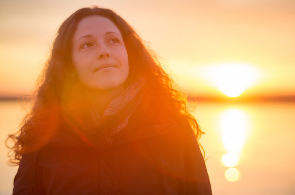 a person reflects by an ocean sunset on international survivors of suicide loss day