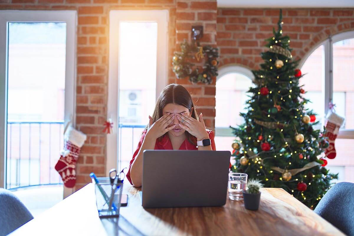 a person in a decorated room rubs their eyes as they deal with holiday stress and anxiety