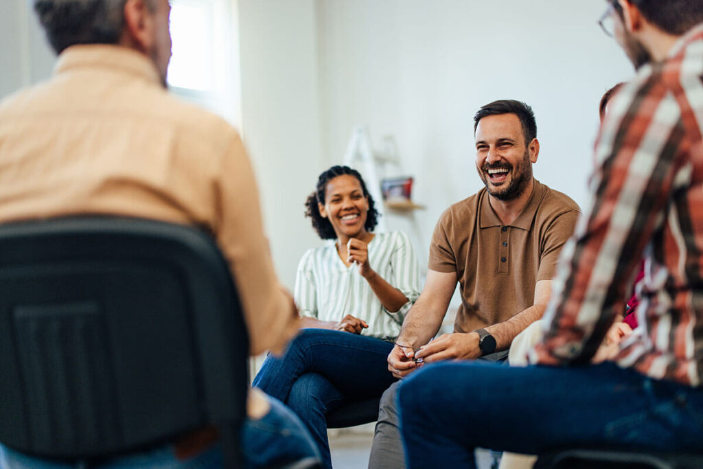 a group smiles during in-person group therapy