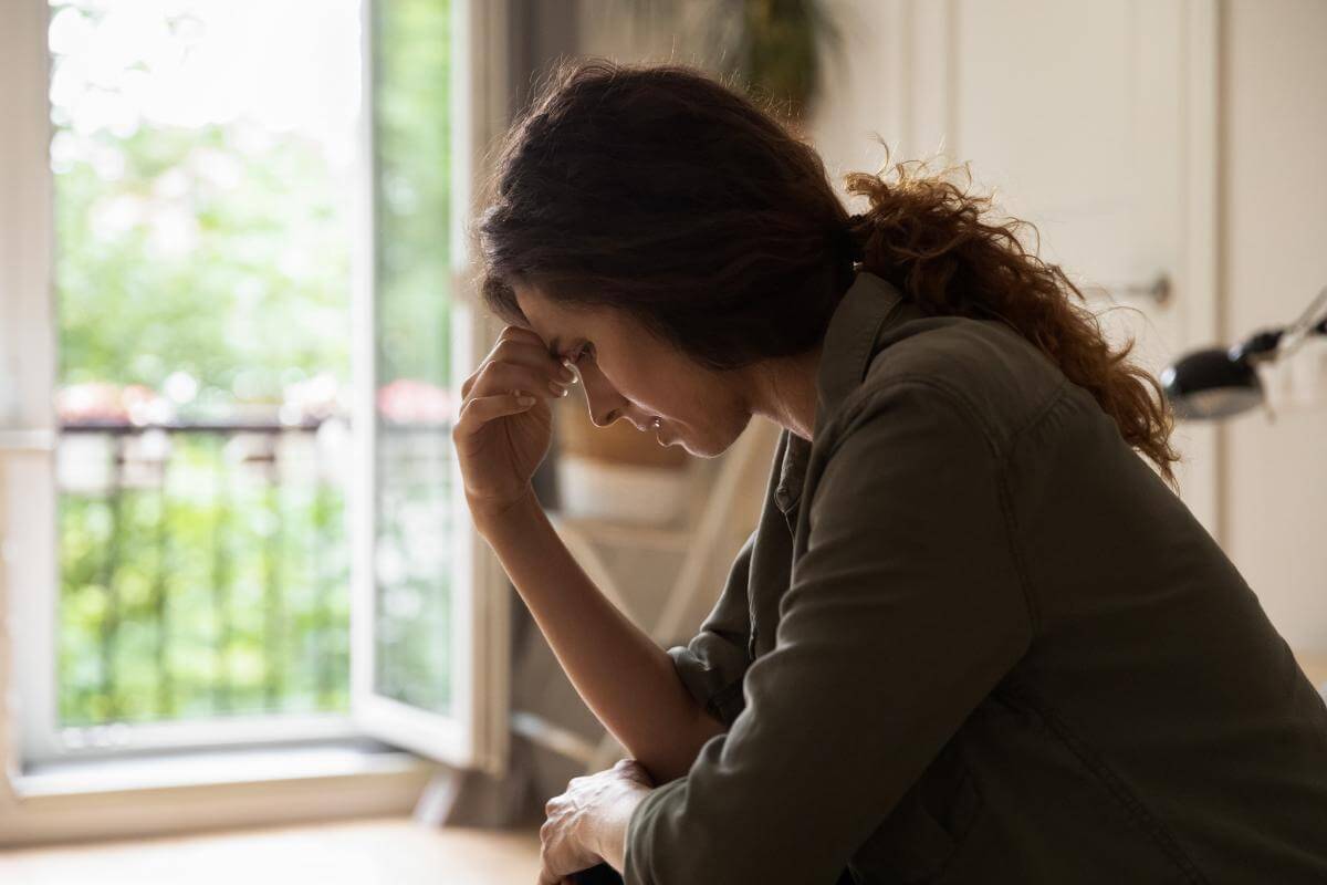 Depressed woman with her hand pressed against her forehead experiencing dual diagnosis symptoms