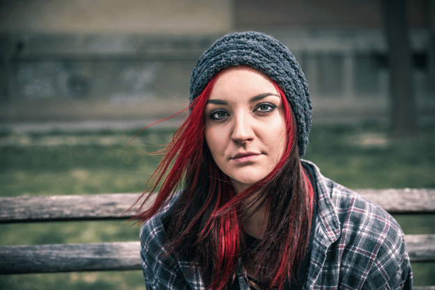 Are-Hallucinogens-Addictive young person with bright red hair wearing hoodie sitting outside while wondering are hallucinogens addictive