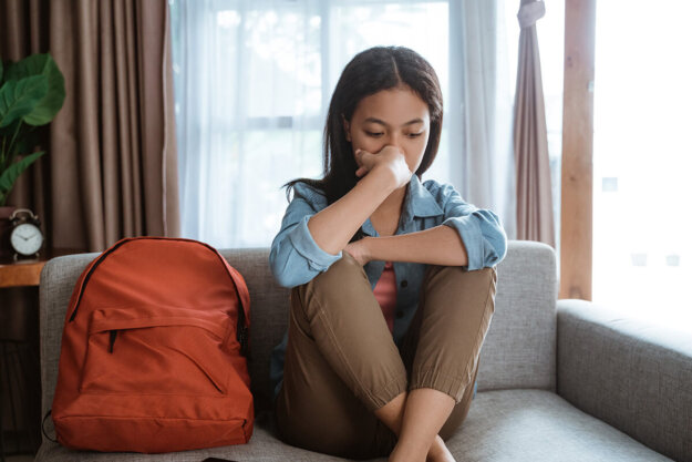 Understanding Teen Addiction-Signs and Symptoms person sitting on couch hugging knees while struggling with teen addiction